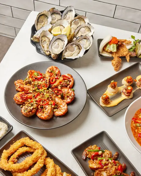 Grilled king prawns, pipis, calamari rings and a dozen oysters on white plates